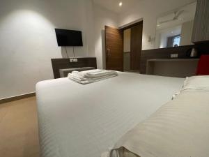 a bedroom with a white bed and a television at Shri Sai Palace in Udupi +5 photos