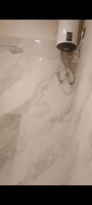 a bathroom with a white marble floor and a chair at a28 ORANGE BRICKS in Kolkata