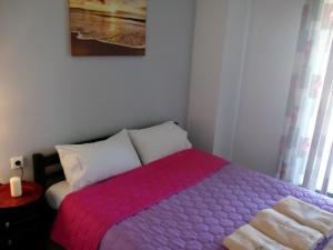 a bedroom with a bed with a pink blanket at Dasea Houses in Ormos Panagias