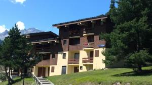 a building with trees and mountains in the background at Résidence Les Campanules - LES CAMPANULES - CA11FC MAE-3147 in Villarodin-Bourget