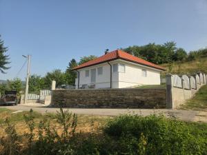 una casa blanca detrás de una pared de piedra con una valla en Kuća snova, en Ilijaš