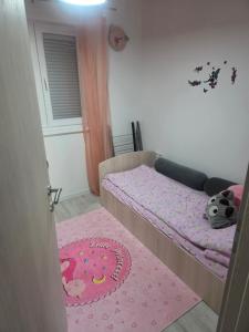 Dormitorio pequeño con cama y alfombra rosa en Kuća snova, en Ilijaš