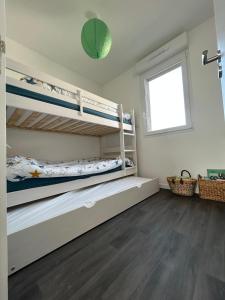 a bedroom with two bunk beds and a window at Maison neuve proche plage et commerces in Stella-Plage
