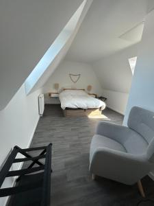 a attic bedroom with a bed and a chair at Maison neuve proche plage et commerces in Stella-Plage