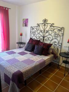 een slaapkamer met een bed met een smeedijzeren hoofdeinde bij LA CASA del CASTAÑO in Aracena