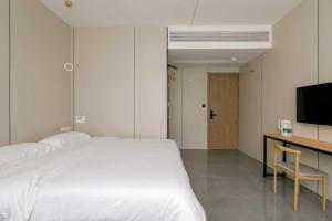 上海市にあるCloud Alley Airport Shuttle Hotelのベッドと机とテレビのある寝室