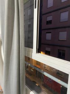 a window with a white curtain next to a building at Rooms availabe in Burriana