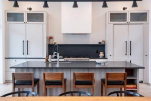 una cucina con armadi bianchi e un'isola con sedie di Ghost Peak Chalet - Ski-In Access a Port Mann
