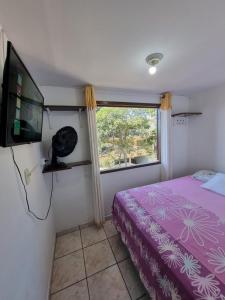 une chambre avec un lit, une télévision et une fenêtre dans l'établissement Pousada Happy - 300m da Praia do Itaguaçú, à São Francisco do Sul