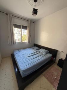 a bedroom with a bed with a blue comforter and a window at Comfortable apartment in Tangier