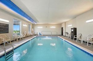 a swimming pool with chairs and tables in a hotel at Cobblestone Hotel & Suites - Bellefontaine in Bellefontaine
