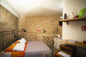 a bedroom with a bed and a brick wall at Lo Scrigno di Alice in Trevi