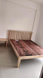 a wooden bed sitting in a corner of a room at Dodamarg Heights in Dodamarg