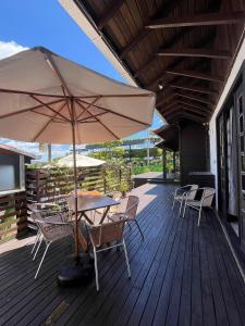 a table and chairs with an umbrella on a deck at Casas Valley Design - Praia do Rosa/SC in Praia do Rosa