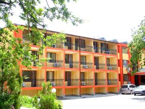 an orange building with cars parked in a parking lot at Park Hotel Kamchia in Kamchia