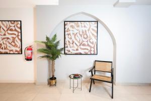 a chair and a plant in a room with two pictures at فندق ديمورا Dimora Hotel in Makkah +16 photos