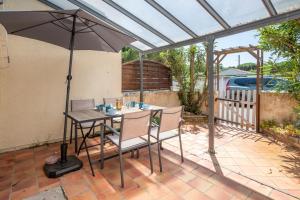 Una mesa y sillas con una sombrilla en un patio. en La Canotière, en Saint-Georges-dʼOléron