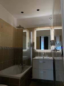 a bathroom with a tub and a sink and a bath tub at Luxor Bastille Hotel in Paris