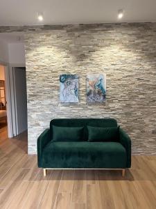 a green couch in front of a brick wall at Dedè&Mimì Come a casa tua in Vasanello