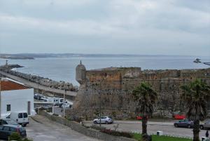 a stone wall with cars parked next to the ocean at O Forte Guest House in Peniche