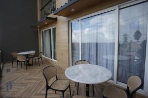 a room with tables and chairs and a large window at ZAR Luxury Suites Murree in Kuldanna
