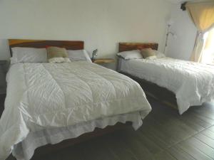 a bedroom with two beds with white comforters at Casita Ikal in Cedro