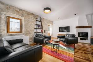 a living room with leather furniture and a stone wall at Villa Cangarela in Višnjan