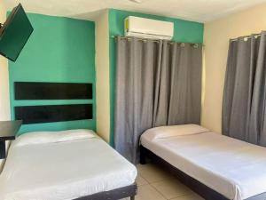 two beds in a room with green walls at Hotel en Acapulco Bora Bora in Acapulco +5 photos