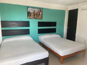 two twin beds in a room with blue walls at Hotel en Acapulco Bora Bora in Acapulco +11 photos