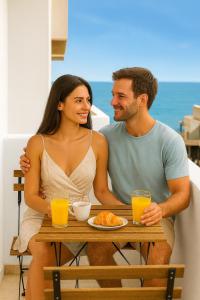 a man and a woman sitting at a table with orange juice at Makas Beach Suites in Hersonissos
