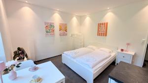 een witte kamer met een bed en twee tafels bij Josephines Studio in Schaffhausen