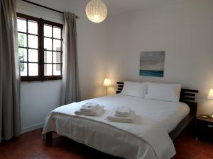 ein Schlafzimmer mit einem weißen Bett mit zwei Handtüchern darauf in der Unterkunft First-Line Oceanfront House in Moledo in Moledo