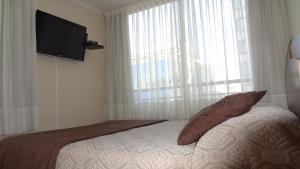 a bedroom with a bed and a flat screen tv at Apartments Bellas Artes in Santiago