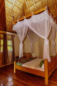 una cama con dosel en una habitación en Nzoghu Heritage Safari Camp, en Kasese