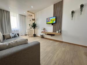 a living room with a couch and a tv on a wall at UrbanSoul Millau in Millau