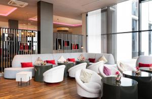 a lobby with white furniture and red pillows at Leonardo Royal Hotel Munich in Munich