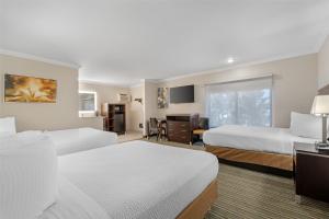 a hotel room with two beds and a desk at Best Western Courtesy Inn Hotel - Anaheim Resort at the Park in Anaheim