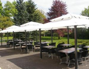 a group of tables and chairs under umbrellas at Hôtel la Régie in Briey