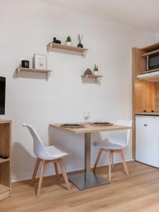a kitchen with a table and two white chairs at Le doux refuge domaine thermal et activités touristiques Amnéville in Amnéville +3 photos