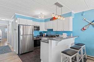 a kitchen with white cabinets and blue walls at Salty Sands 302 in Ocean City