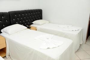 two beds with white sheets in a room at Gran Fortaleza Hotel in Goiânia