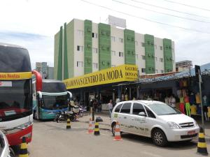 a bus and a white car parked in front of a building at Gran Fortaleza Hotel in Goiânia