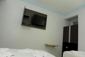 a room with two beds and a tv on the wall at Gran Fortaleza Hotel in Goiânia