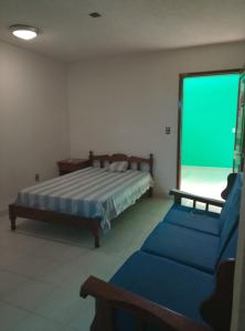 ein Schlafzimmer mit einem Bett und einer Couch und einem Greenscreen in der Unterkunft F H Hostel in Chetumal