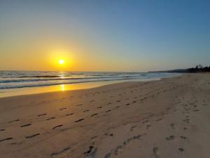 a sunset on the beach with footprints in the sand at Sarvehuts Kashid in Kashid
