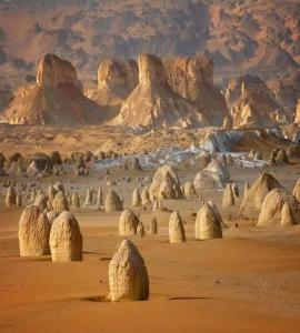 a desert with rocks and mountains in the distance at White desert camp in Bawiti