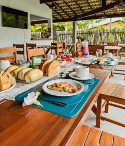 a long wooden table with a plate of food on it at Môzzi Barra Grande in Barra Grande