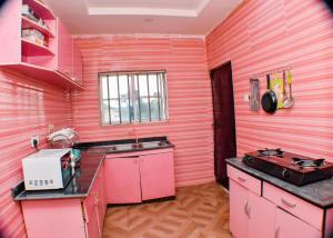 a pink kitchen with a sink and a stove at AC Apartment in Asaba