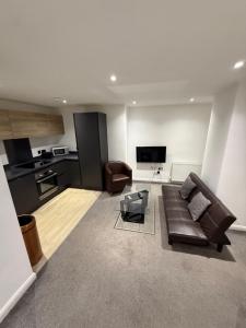 a living room with a brown couch and a kitchen at Premier Serviced Apartmetns oldham road Manchester in Manchester