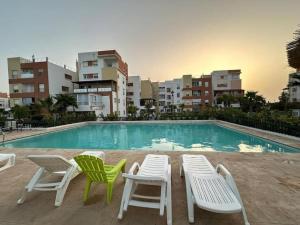 a swimming pool with lawn chairs and chairs next to a building at Beautiful apart with sea view in Tangier